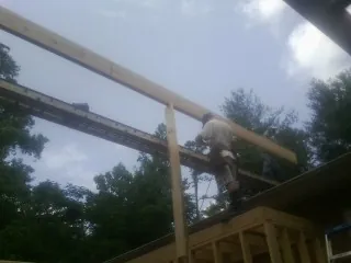 Carpenter setting a ridge beam over a new addition frame — Ice Dam Removal by Roofing Brothers in Tarrytown