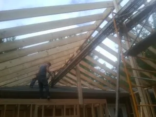 Rafters going up over a new addition with a worker on the wall in Tarrytown