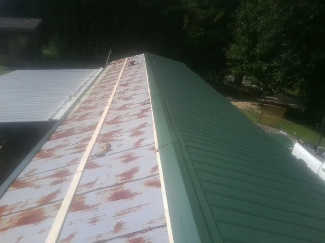 Old rusted panels beside newly installed green metal roofing — Wind Damage Roof Repair by Roofing Brothers in Tarrytown