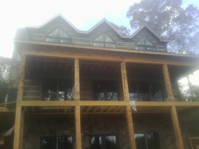 Dormers and porch framing on a large log home under construction — Roof Coating work by our crew in Tarrytown