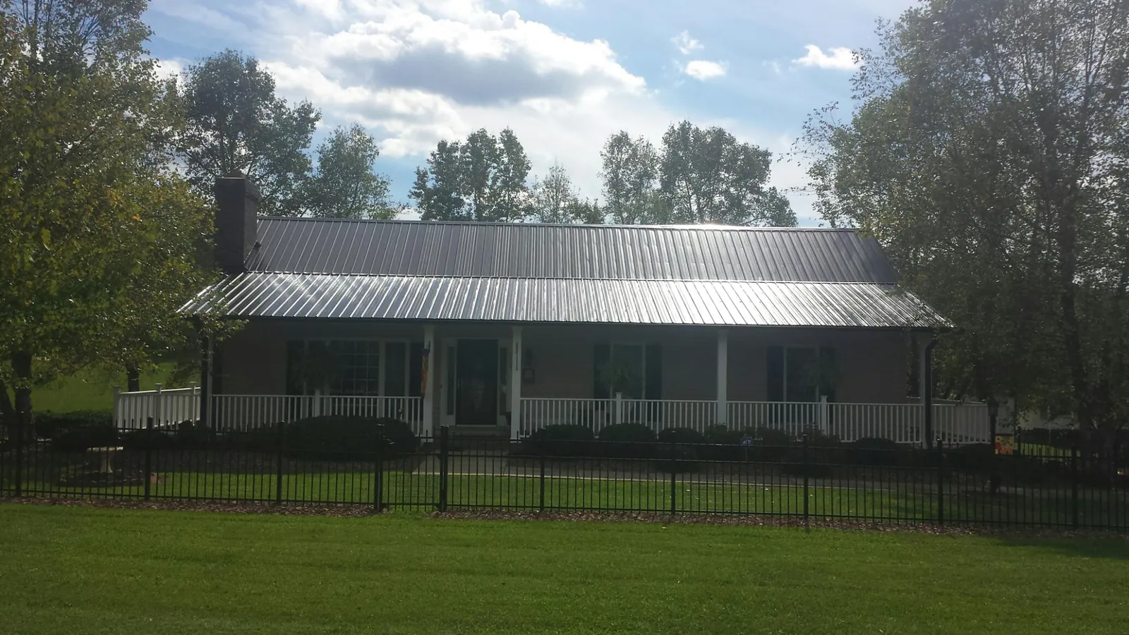Gray metal roof on a brick ranch with a full width front porch — Gutter Guard Installation work by our crew in Tarrytown