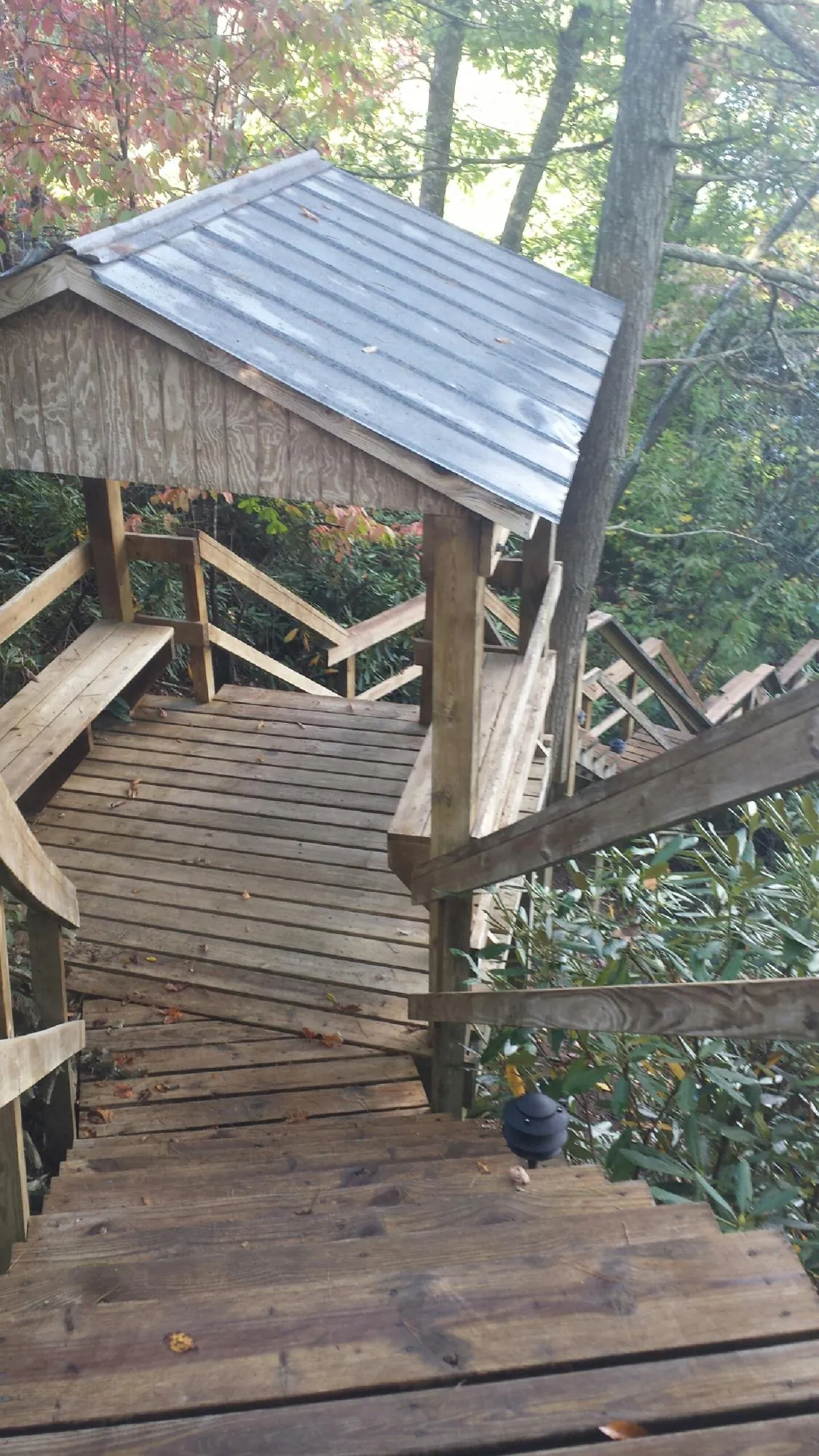 Metal roofed shelter over wooden steps on a wooded walkway — Skylight Repair & Installation work by our crew in Tarrytown
