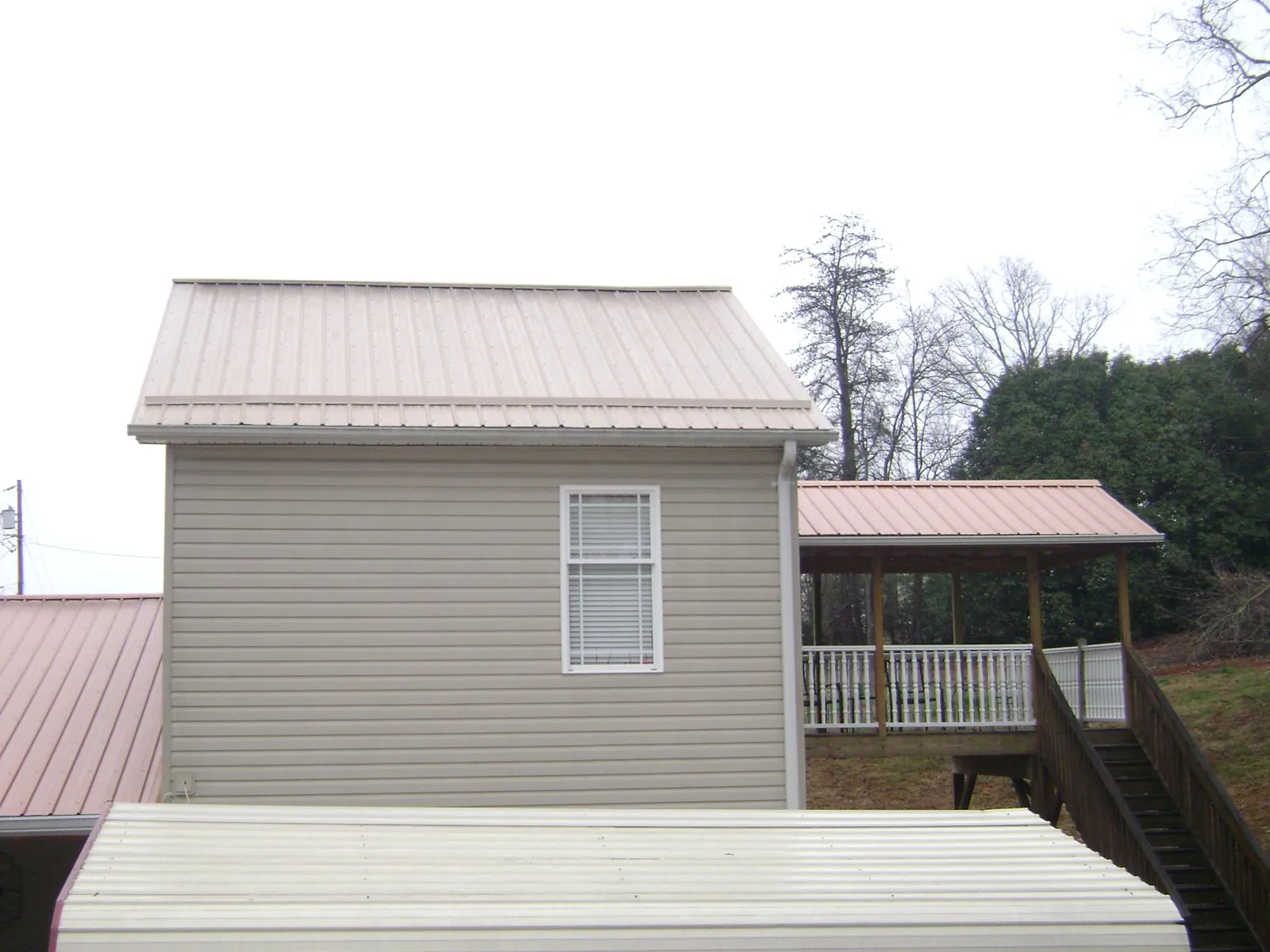 Tan metal roofs on a two story addition and attached porch, from a Roof Replacement job in Tarrytown